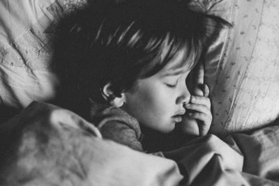 睡在白色枕头上的女孩的灰度照片